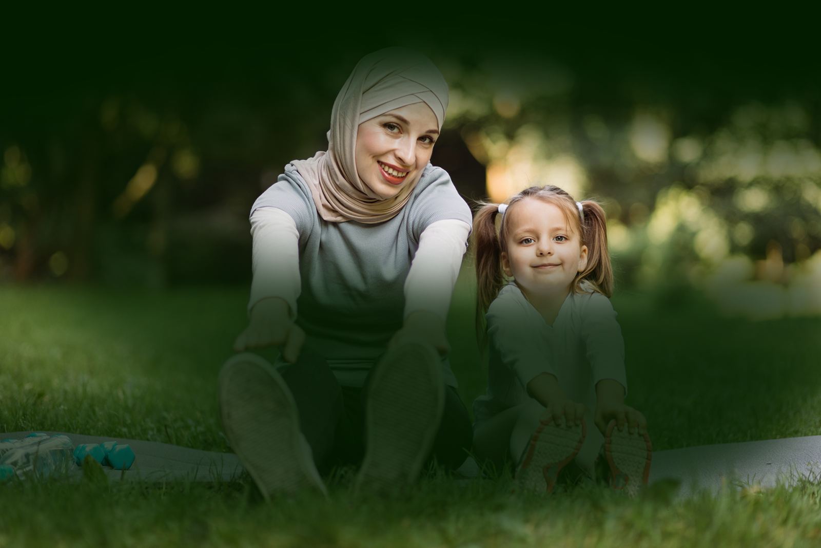 A mother and her daughter stretching together in a park