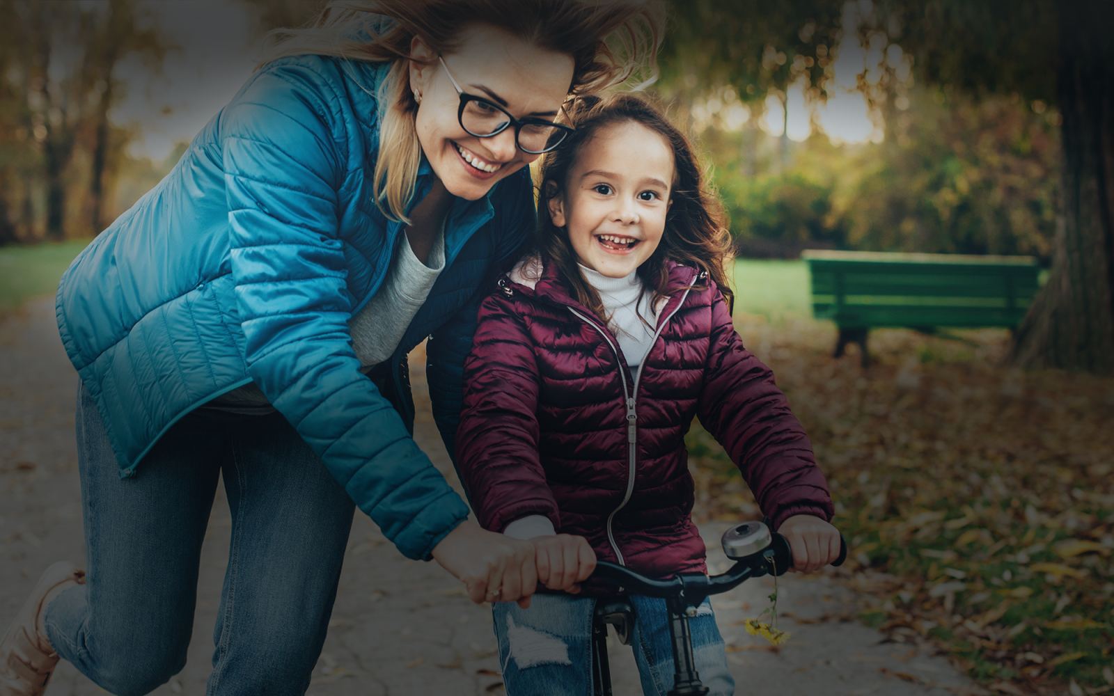 A mother teaching her daughter to ride a bicycle